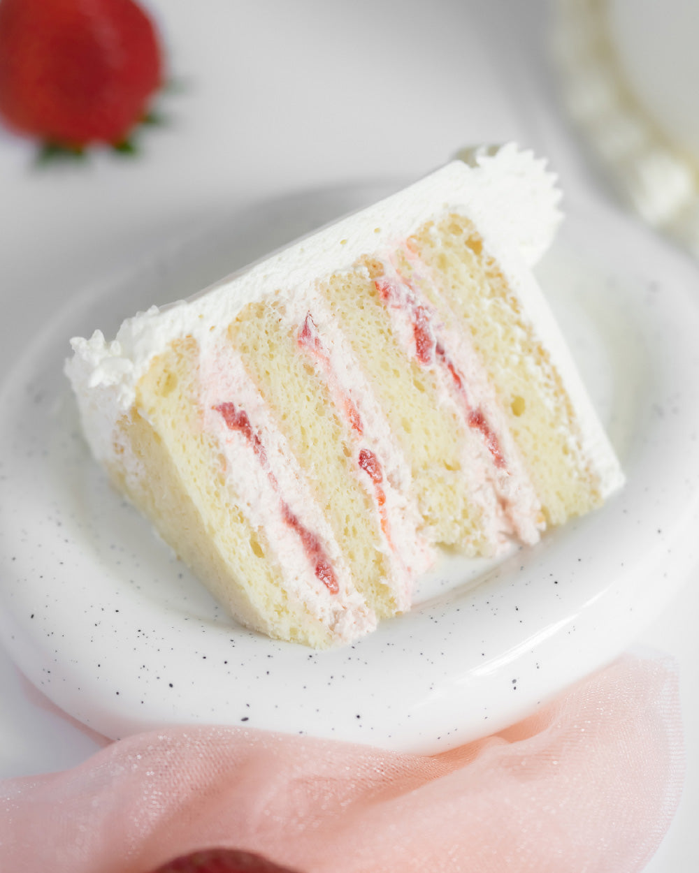 A slice of Strawberry Cake made of Vanilla Sponge Cake,  Strawberry Fresh Cream,  Fresh Strawberries & Chantilly Cream